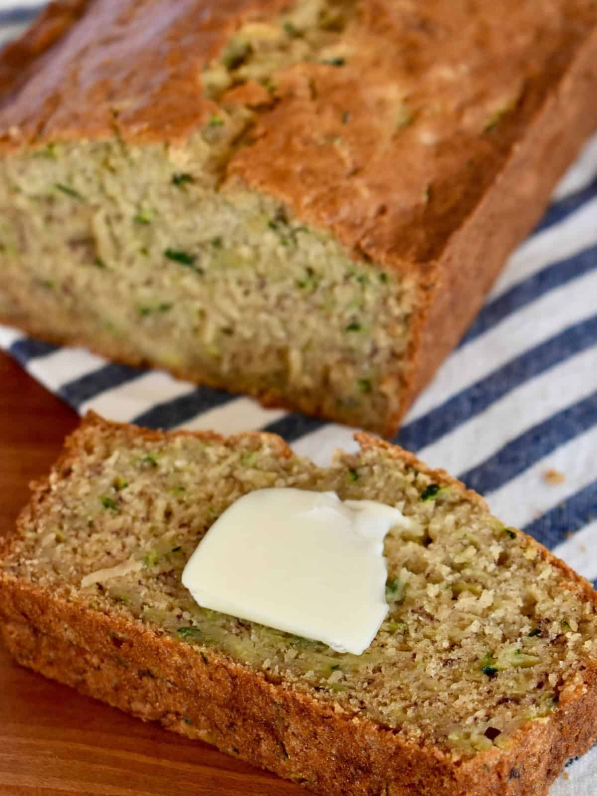 Slice of zucchini banana bread with butter on it.