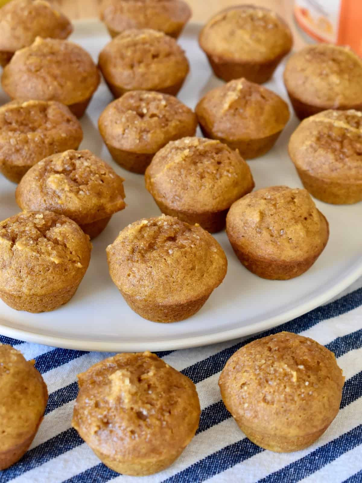 Mini pumpkin muffins on a white plate with a striped napkin. 