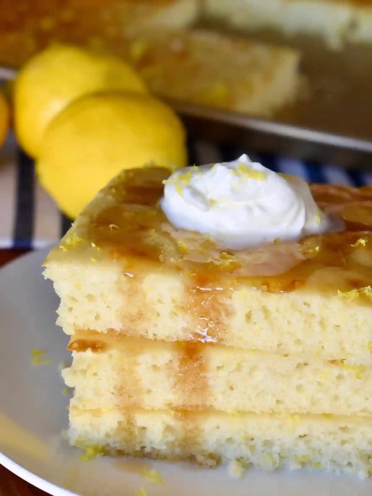 Sheet Pan Lemon Ricotta Pancakes stacked on a white plate with whipped cream on top.