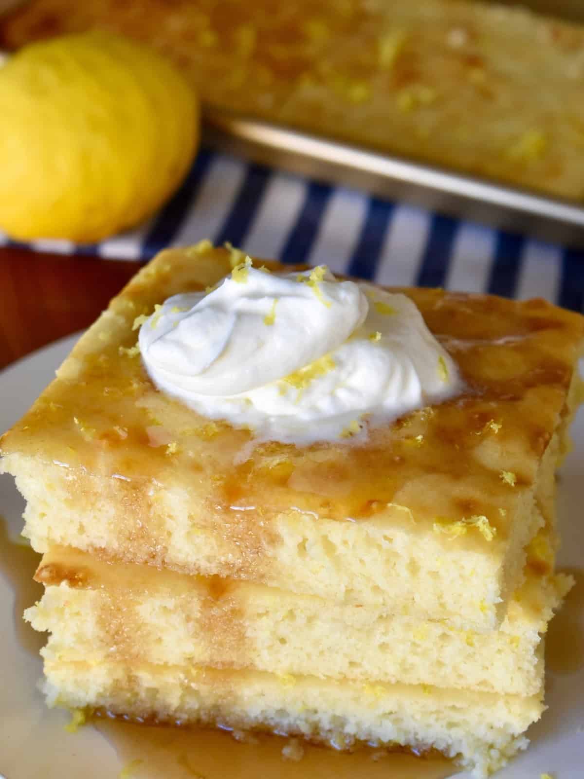 Sheet Pan Lemon Ricotta Pancakes stacked on a white plate with whipped cream on top.